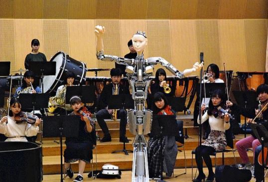 Un robot con forma de androide guía a una orquesta en teatro